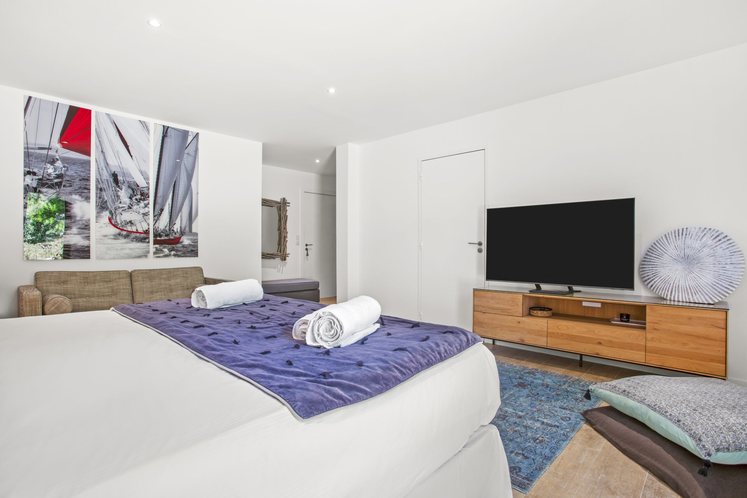 The Sailing Suite bedroom interior with TV area, wooden furniture and nautical details