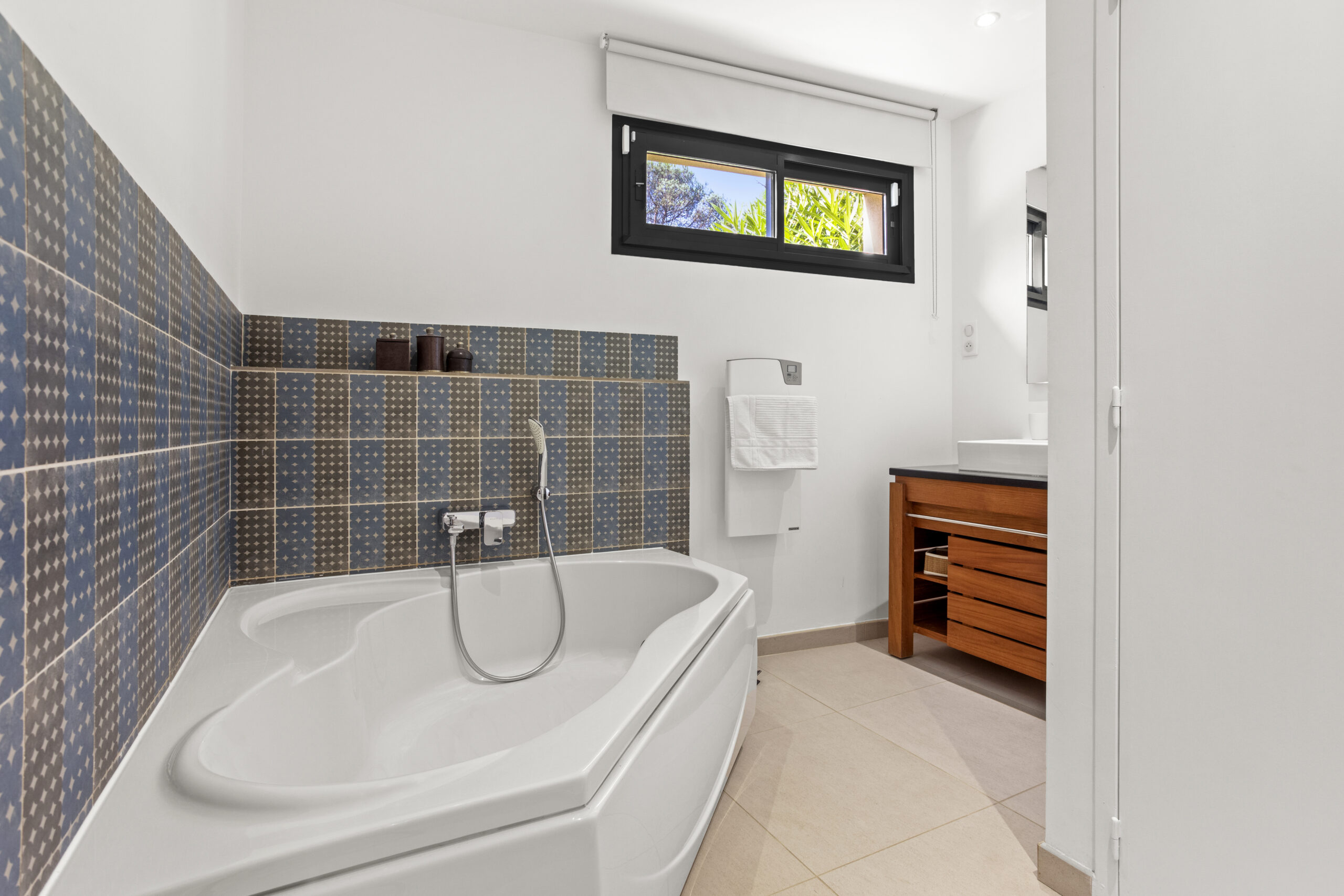Bathroom of the soft blue suite at Villa Cycas featuring a bathtub, patterned tiles and natural light in Ramatuelle