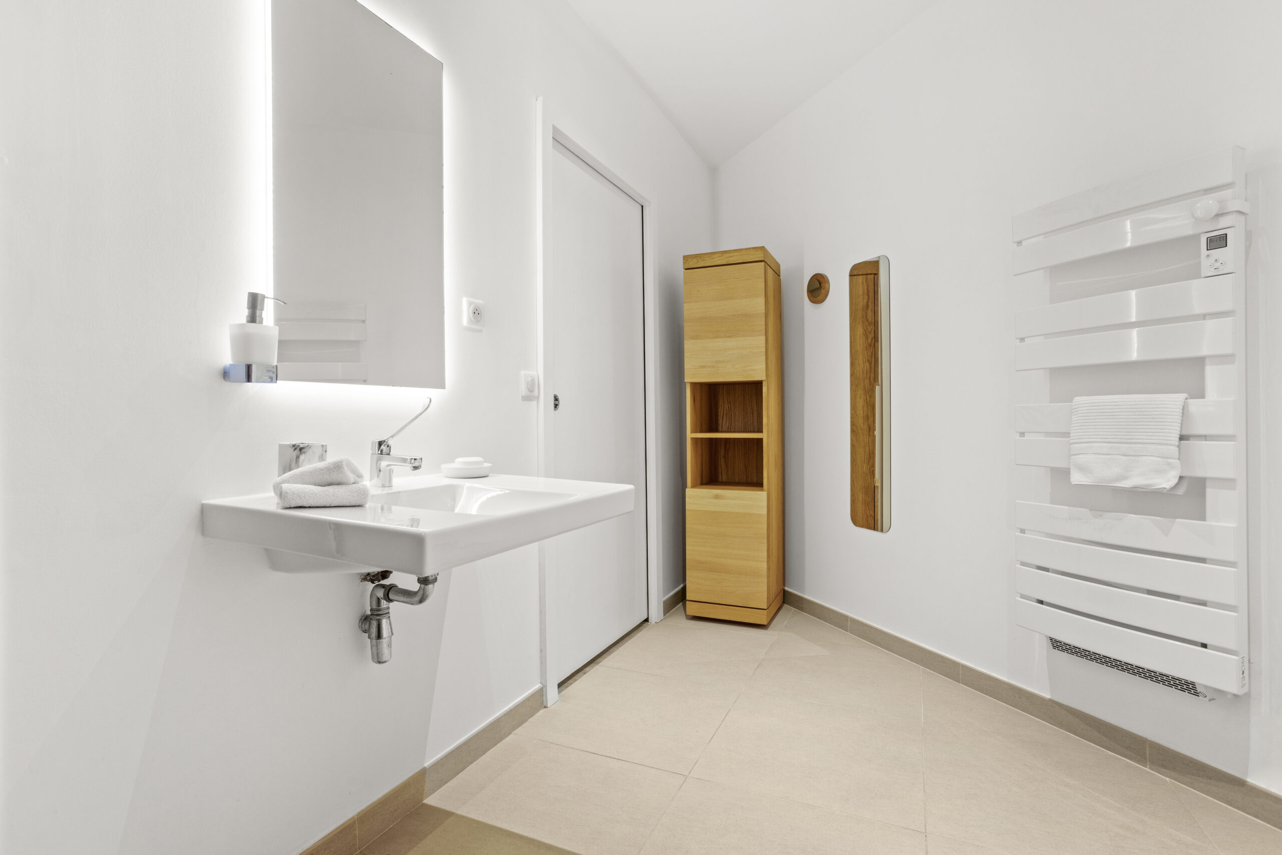 The Sun Deck Suite bathroom with minimalist sink, illuminated mirror and wooden storage